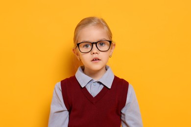 Photo of Little girl with glasses on orange background. Dreaming of future profession