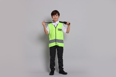 Photo of Boy pretending to be policeman on light grey background. Dreaming of future profession