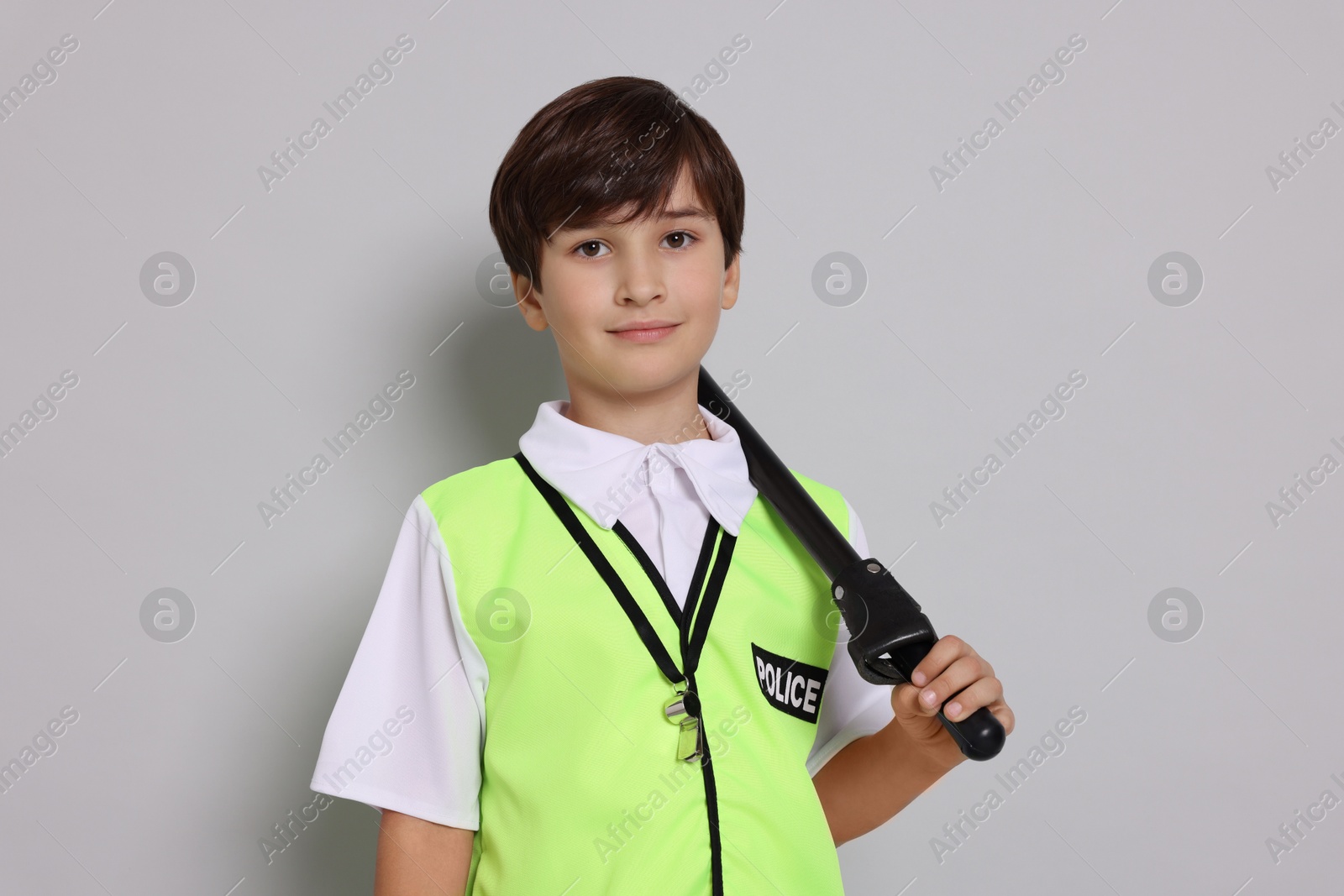 Photo of Boy pretending to be policeman on light grey background. Dreaming of future profession