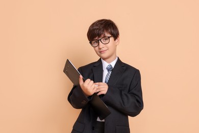 Photo of Boy with clipboard pretending to be accountant on beige background. Dreaming of future profession