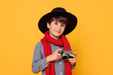 Photo of Boy with camera pretending to be photographer on orange background. Dreaming of future profession