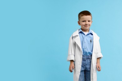 Photo of Little boy pretending to be doctor on light blue background, space for text. Dreaming of future profession