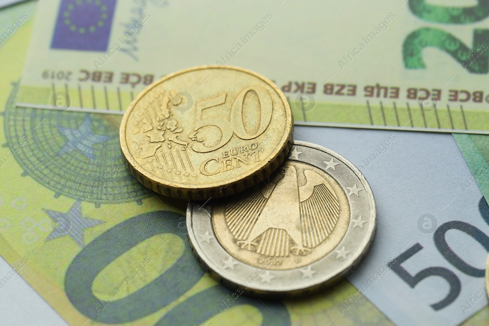 Photo of Different coins on euro banknotes, closeup view