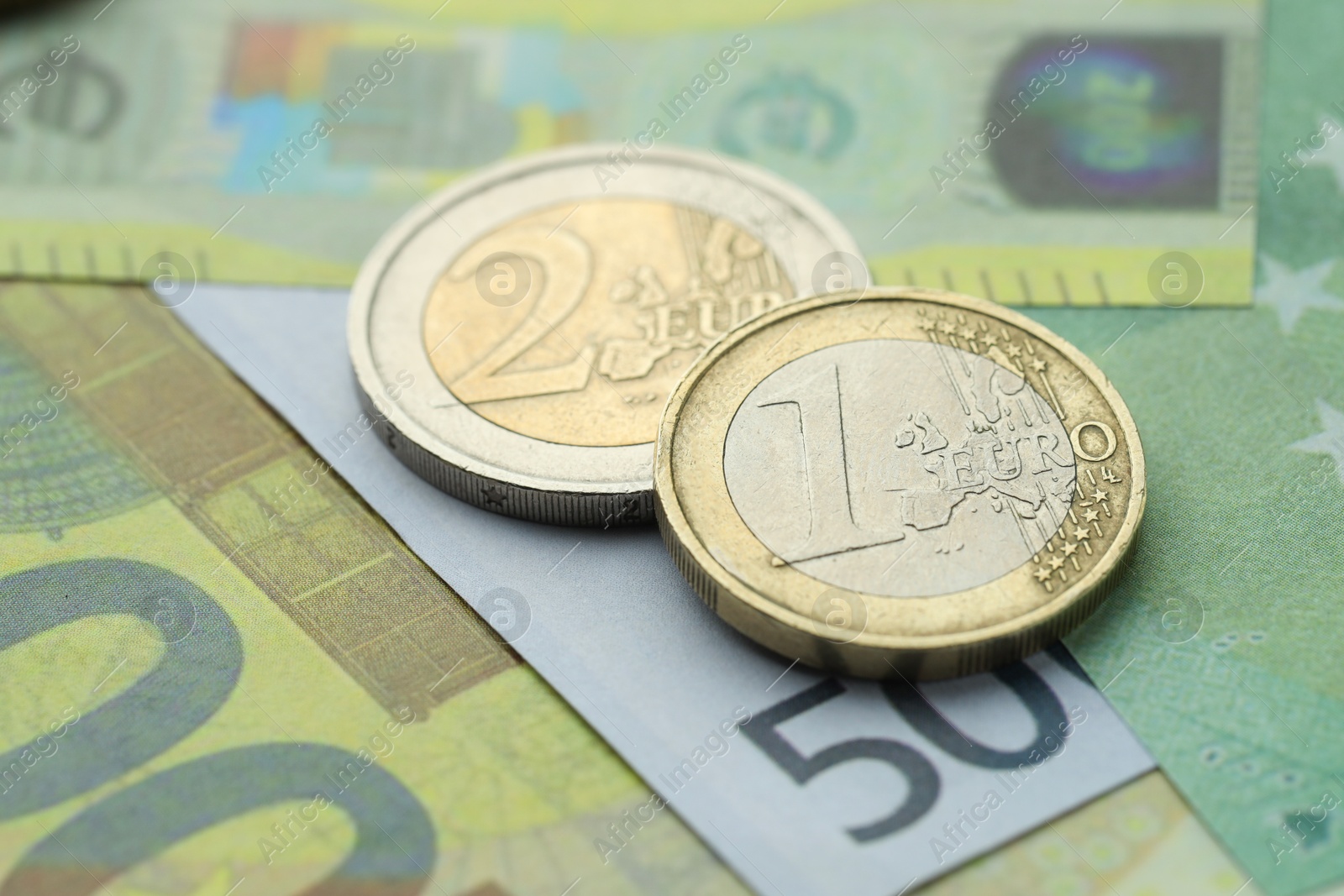 Photo of Different coins on euro banknotes, closeup view