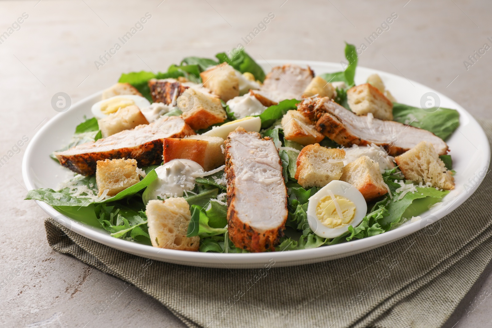 Photo of Tasty Caesar salad with chicken on light grey table, closeup