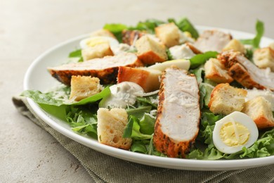 Photo of Tasty Caesar salad with chicken on light grey table, closeup