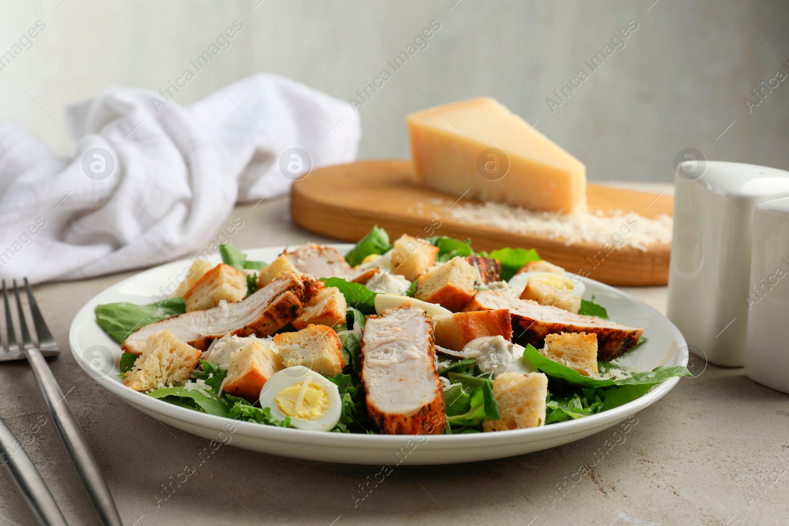 Photo of Tasty Caesar salad with chicken on light grey table