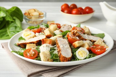 Photo of Tasty Caesar salad with chicken and tomatoes on white wooden table