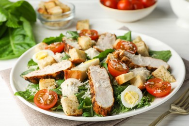 Photo of Tasty Caesar salad with chicken and tomatoes on white wooden table, closeup