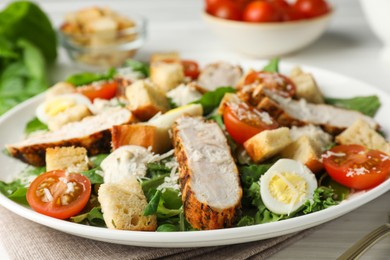 Photo of Tasty Caesar salad with chicken and tomatoes on white wooden table, closeup