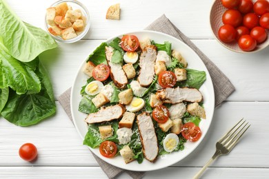 Photo of Tasty Caesar salad with chicken and tomatoes on white wooden table, flat lay