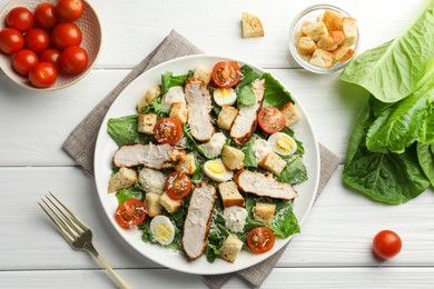 Photo of Tasty Caesar salad with chicken and tomatoes on white wooden table, flat lay