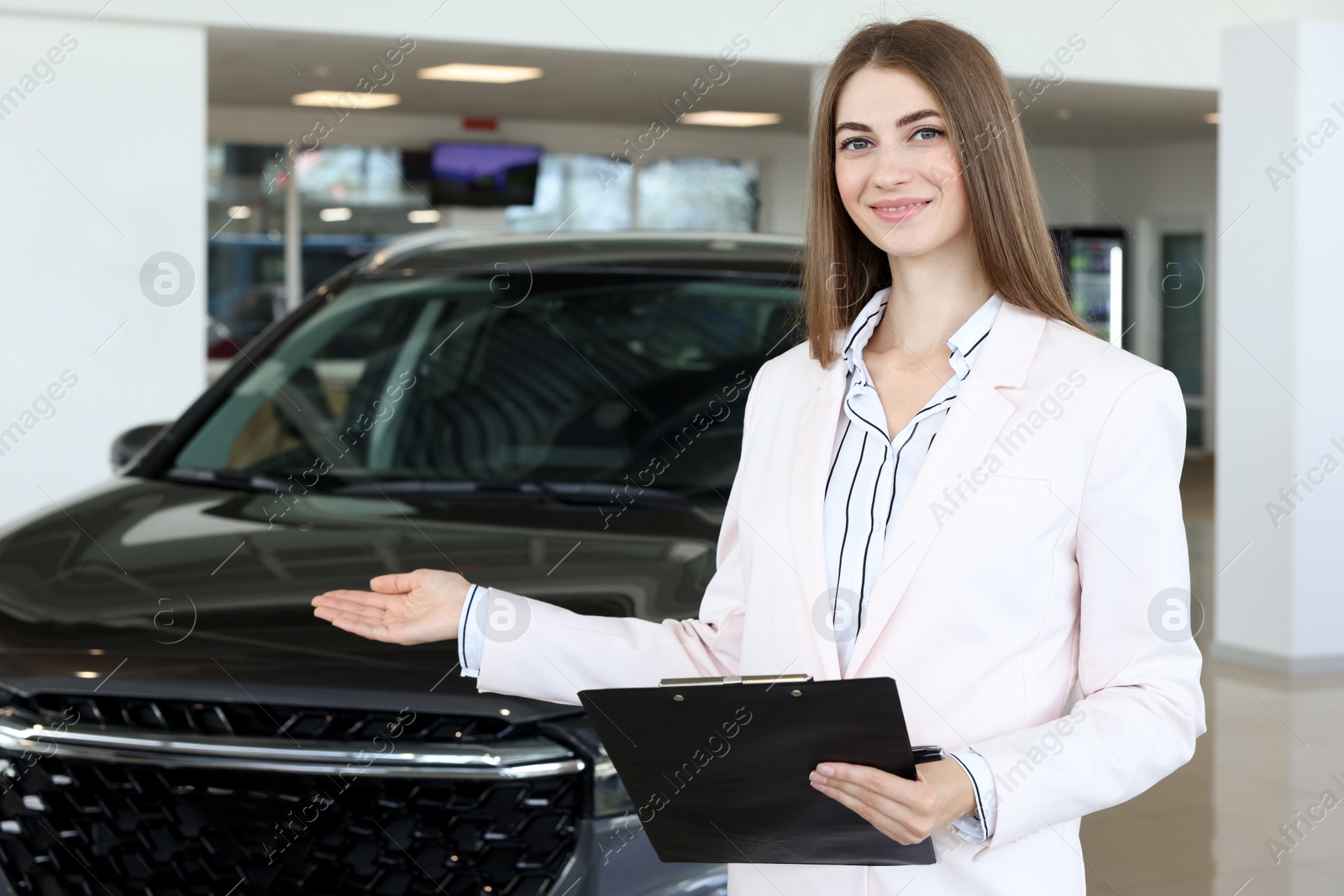 Photo of Happy saleswoman near new black car in salon