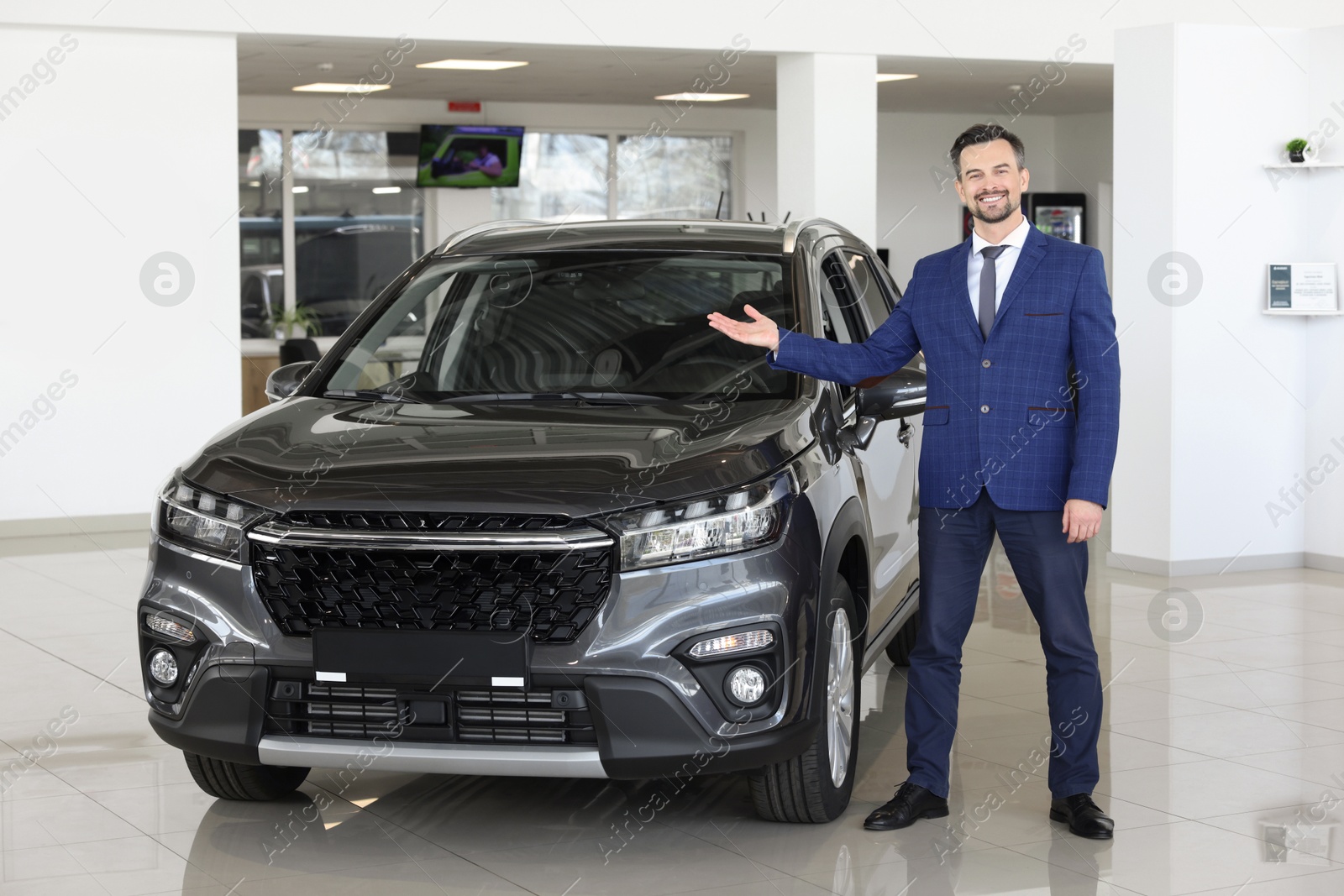 Photo of Happy salesman near new black car in salon