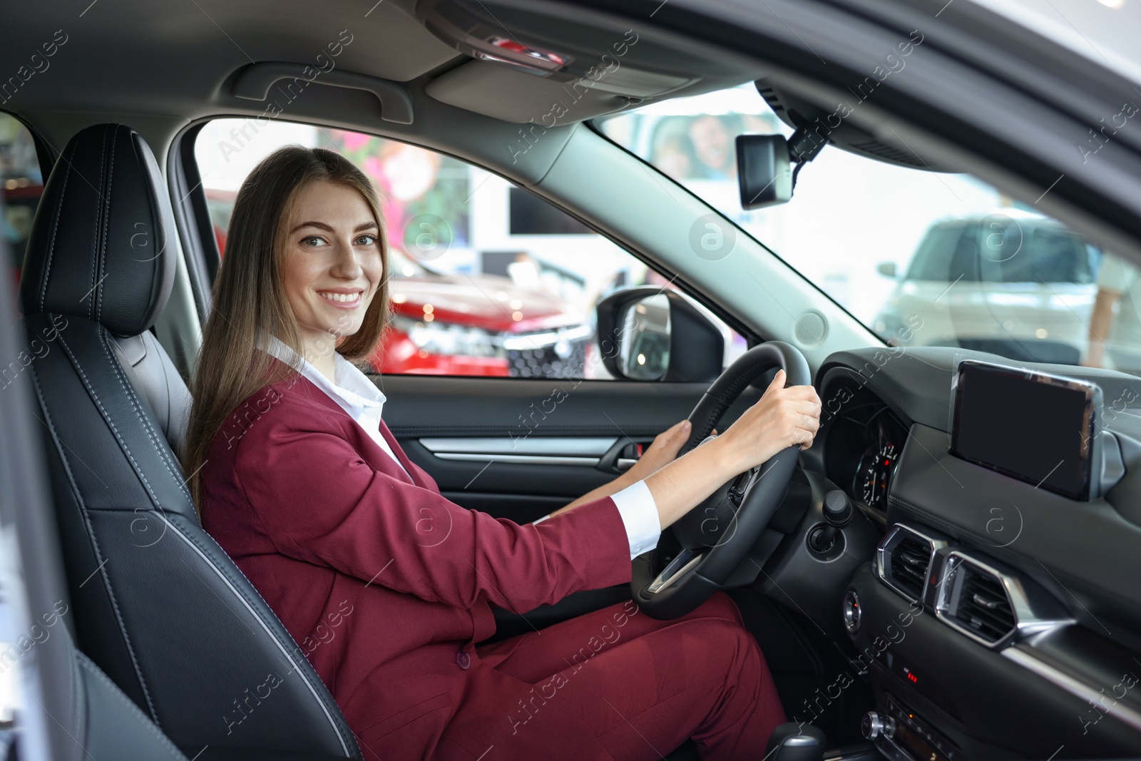 Photo of Young woman inside new car in salon