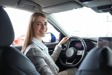 Photo of Young woman inside new car in salon