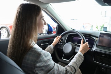 Photo of Young woman inside new car in salon