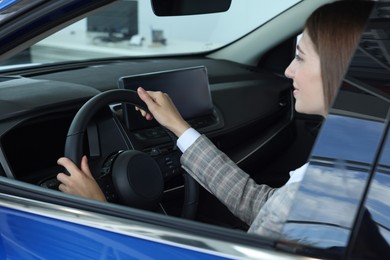 Photo of Young woman inside new blue car in salon