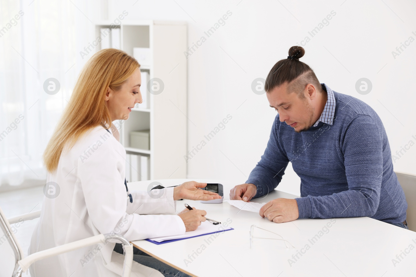 Photo of Nutritionist consulting overweight man at table in clinic