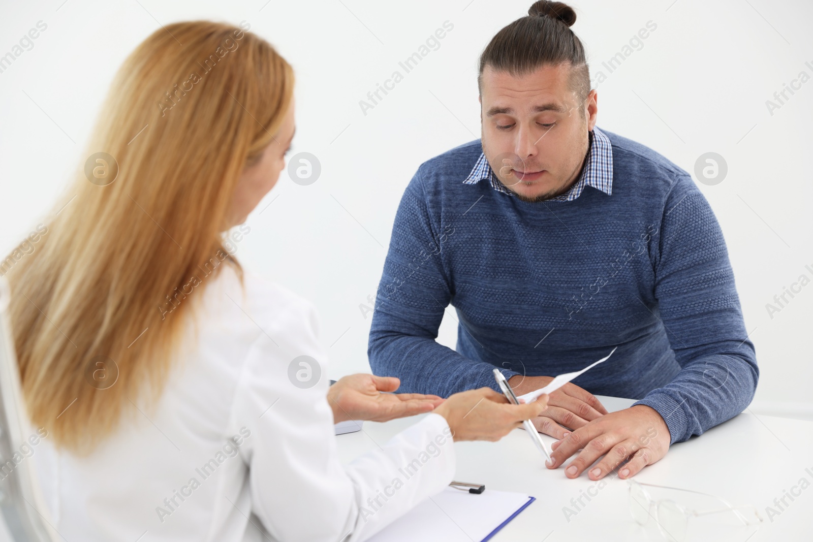 Photo of Nutritionist consulting overweight man at table in clinic