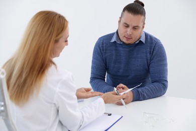 Photo of Nutritionist consulting overweight man at table in clinic