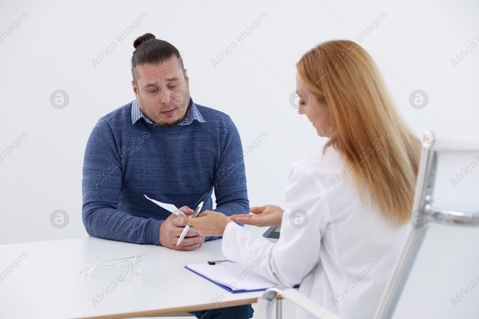 Photo of Nutritionist consulting overweight man at table in clinic