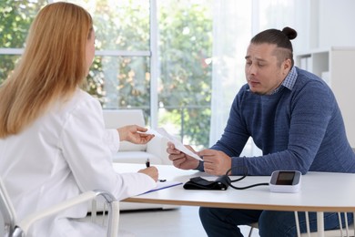 Photo of Nutritionist consulting overweight man at table in clinic