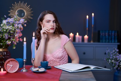 Photo of Beautiful young woman sitting at table in room. Fashion vintage style portrait