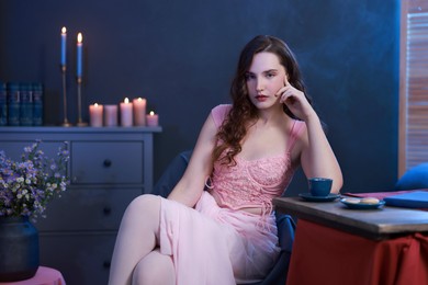 Photo of Beautiful young woman sitting at table in room. Fashion vintage style portrait