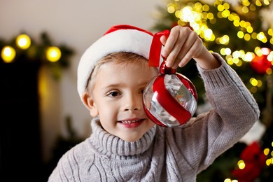 Photo of Little boy with Christmas ornament at home