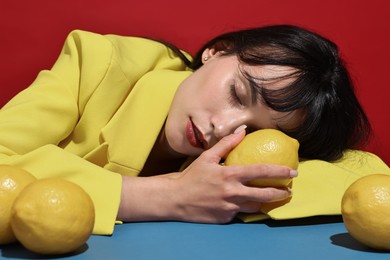 Photo of Woman with lemons at blue table on red background