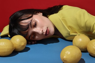 Woman with lemons at blue table on red background