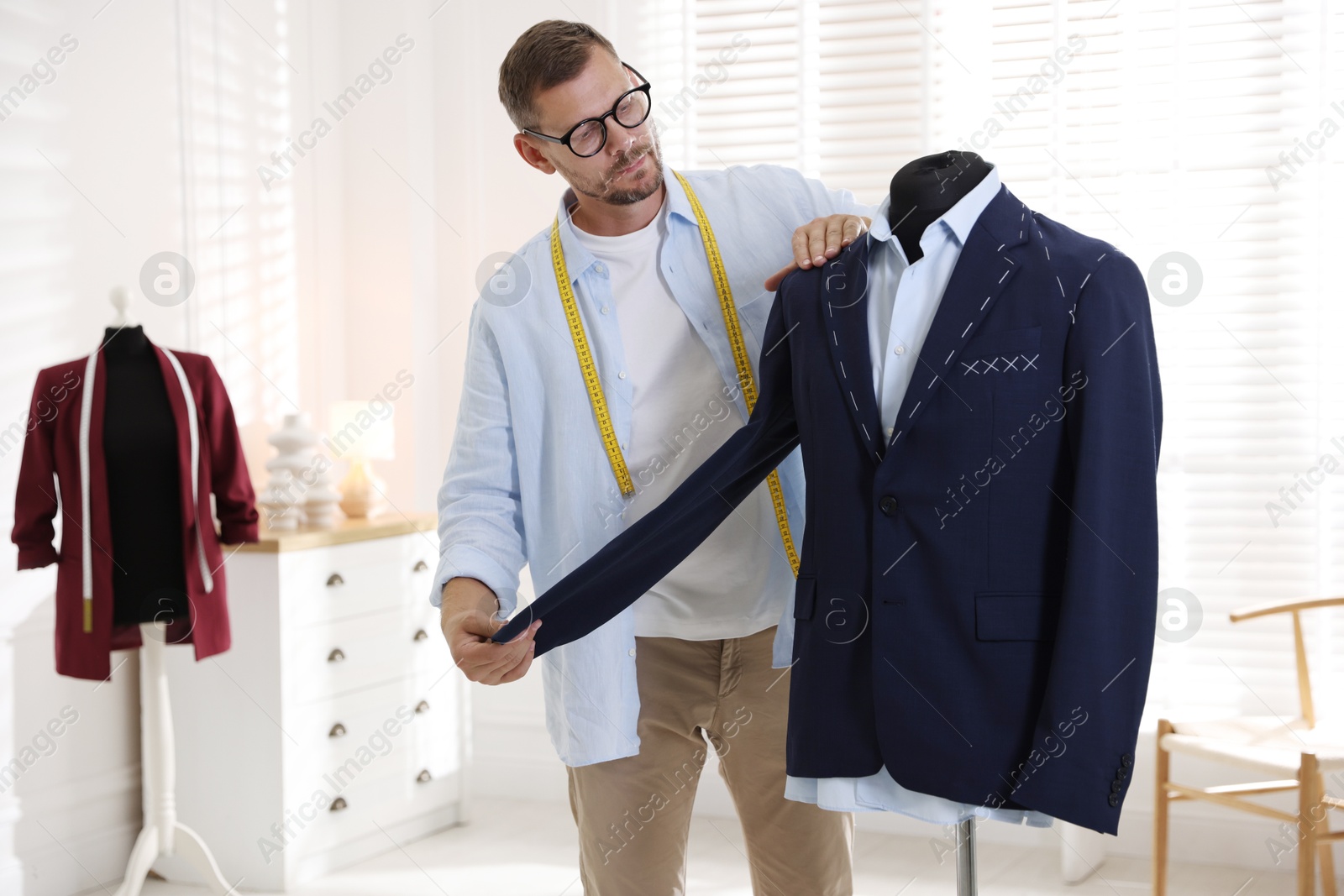 Photo of Man measuring black jacket with tape in atelier, closeup