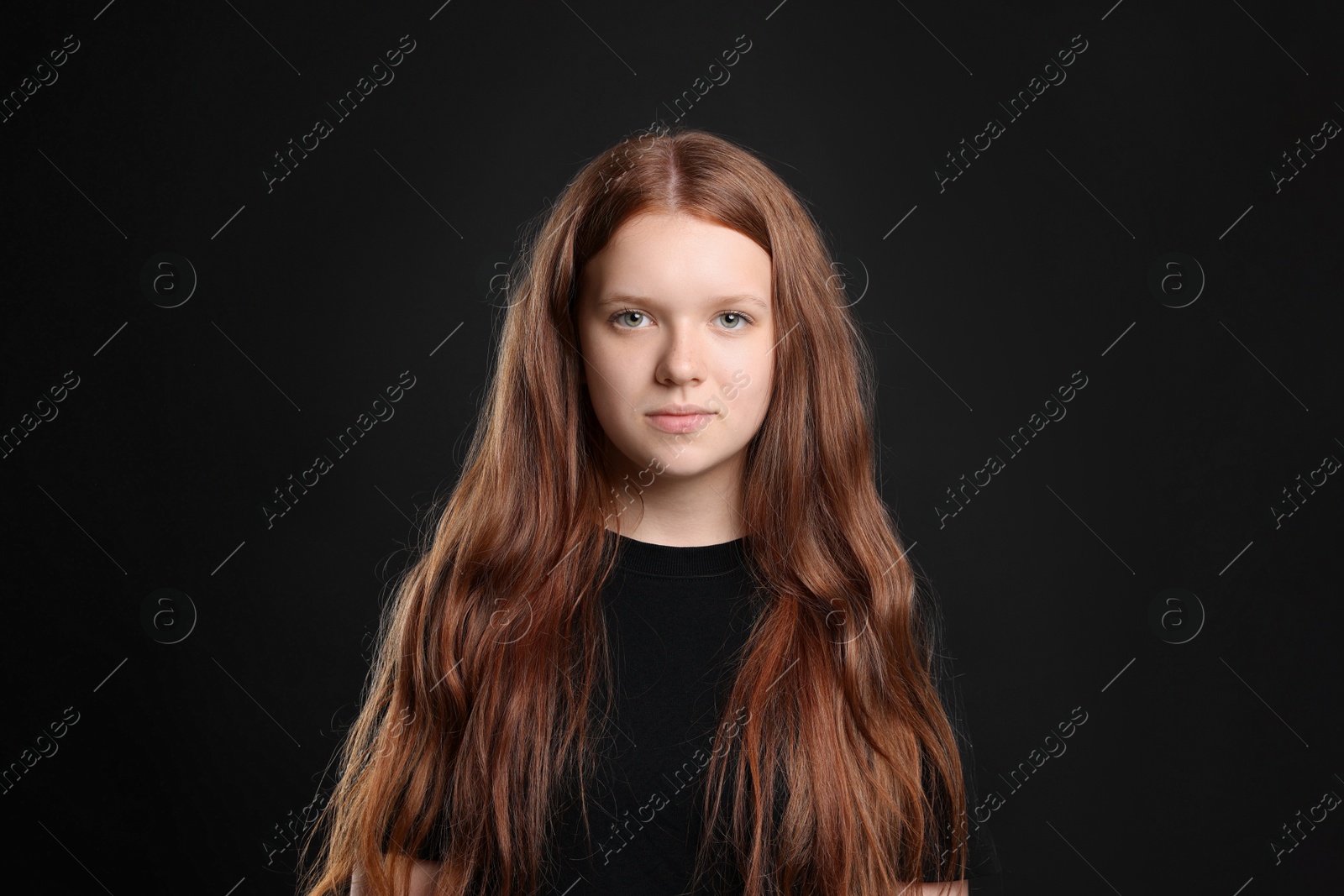 Photo of Pretty red-haired teenage girl on black background