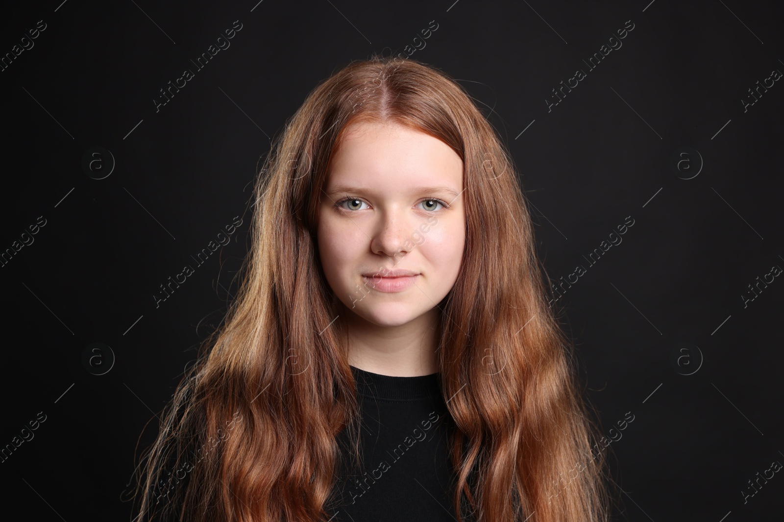 Photo of Pretty red-haired teenage girl on black background