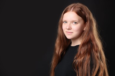 Photo of Pretty red-haired teenage girl on black background. Space for text