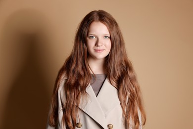 Photo of Pretty red-haired teenage girl on dark beige background