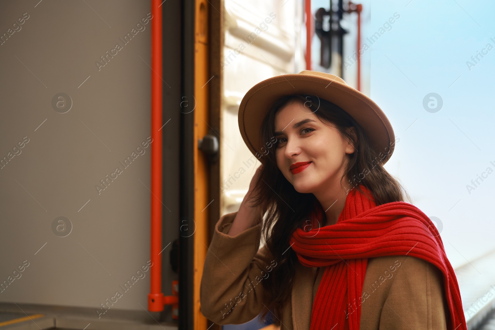 Photo of Woman with red scarf near train on platform of railway station