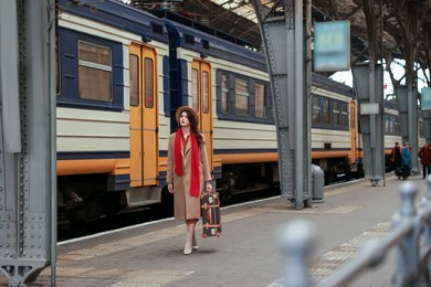 Woman with suitcase on platform of railway station