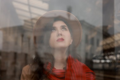 Photo of Woman with red scarf at railway station, view through glass window