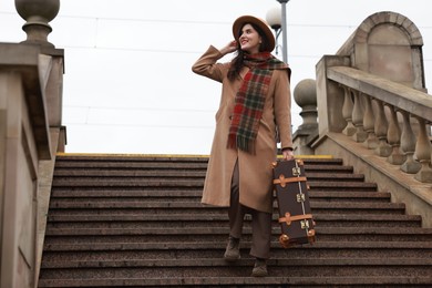 Photo of Beautiful woman with suitcase on stairs outdoors