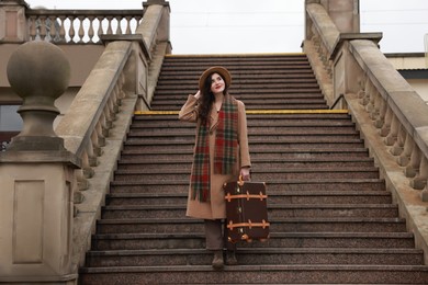 Photo of Beautiful woman with suitcase on stairs outdoors