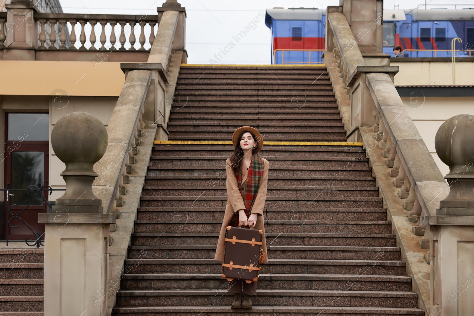 Photo of Beautiful woman with suitcase on stairs outdoors