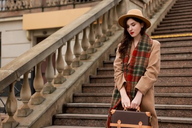 Photo of Beautiful woman with suitcase near stairs outdoors