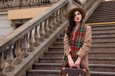 Photo of Beautiful woman with suitcase near stairs outdoors