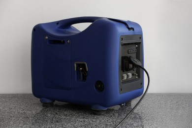 Photo of Modern portable power station near beige wall indoors