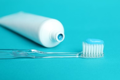 Photo of Toothbrush with toothpaste and tube on light blue background, closeup