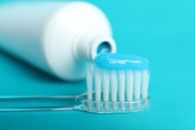 Photo of Toothbrush with toothpaste and tube on light blue background, closeup