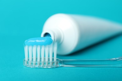 Photo of Toothbrush with toothpaste and tube on light blue background, closeup