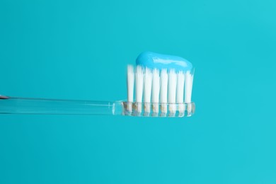 Photo of Toothbrush with toothpaste in air on light blue background, closeup